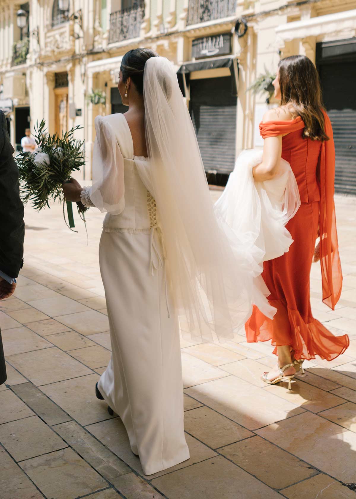 Novia y cuñada llevando la cola del vestido camino de la iglesia