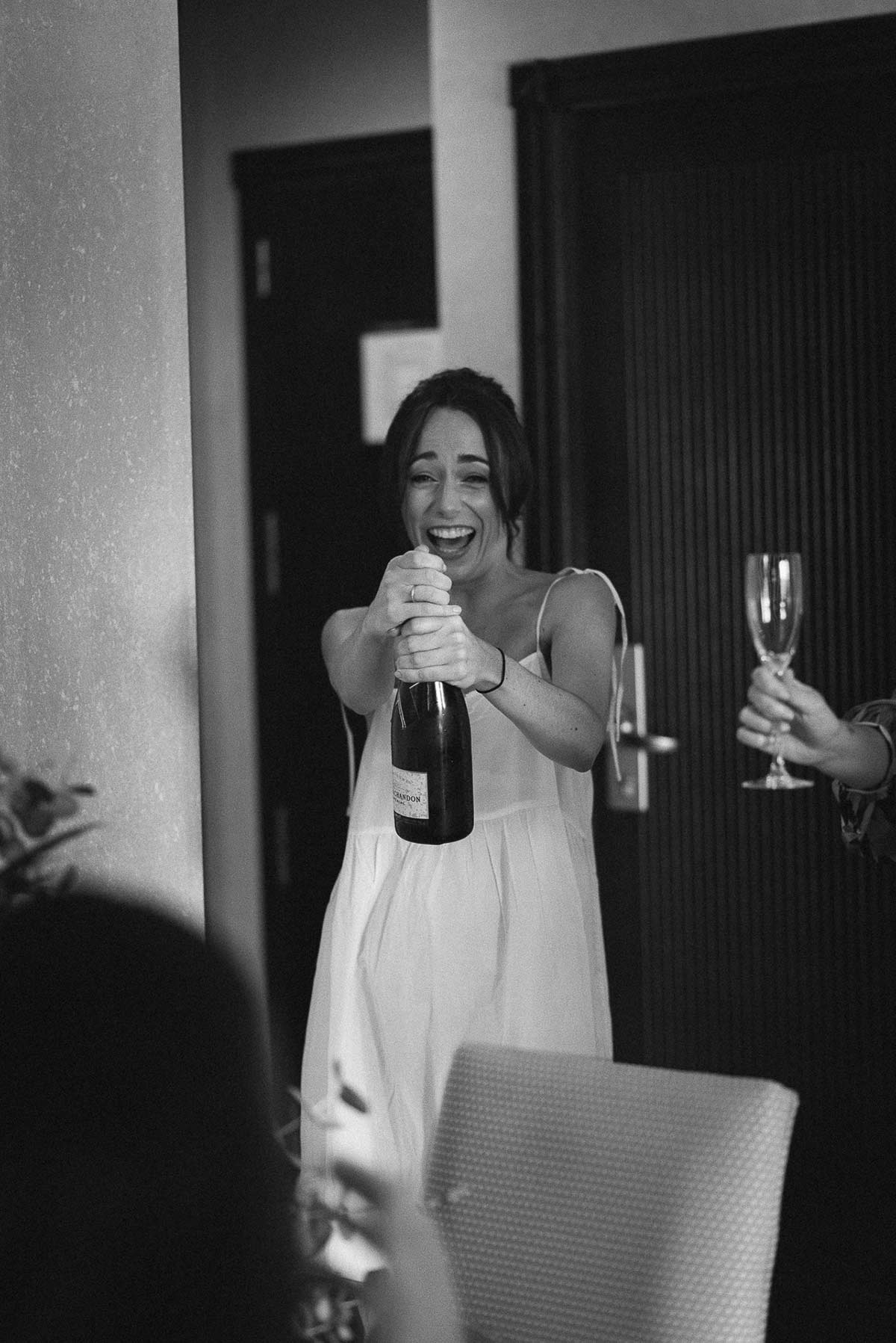 Novia con botella de champán en los preparativos